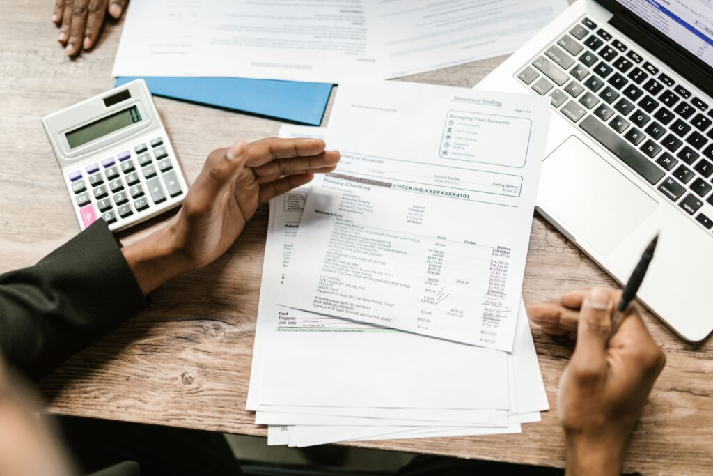 Home Hands holding financial documents with calculator and laptop on office desk, business analysis scene.